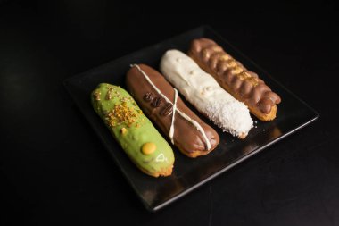 Siyah arka planda tatlı ve renkli ekler. Fransız ekleriName