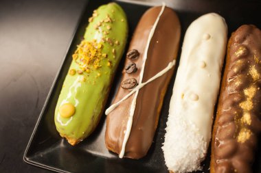 Siyah arka planda tatlı ve renkli ekler. Fransız ekleriName