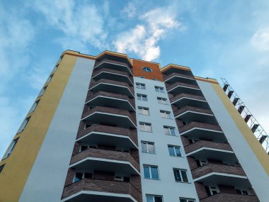 Güneşli bir günde mavi gökyüzü olan modern bir apartman. Modern bir apartmanın cephesi