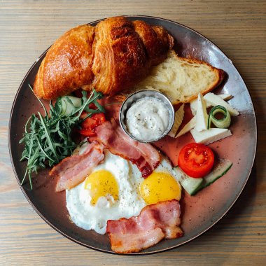 Kızarmış yumurta, salata yapraklı, ızgara mantarlı ve vişneli domatesli kruvasan sandviçli leziz kahvaltı.