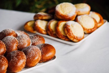 Beyaz masa arkaplanındaki bir tabakta süzme peynirli çörek.
