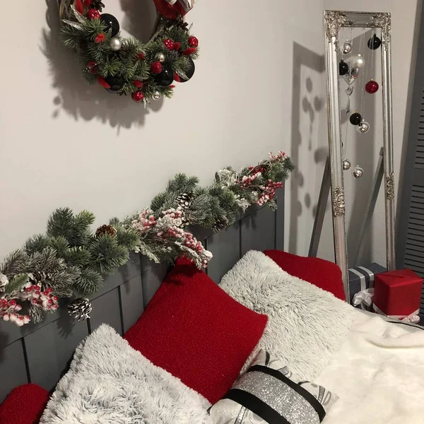 Bedroom decorated by Christmas. Cozy light interior, New Year\'s fir-tree decorated with toys and garlands