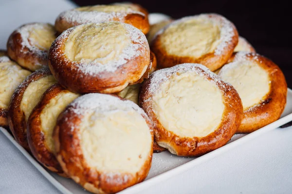 Beyaz masa arkaplanındaki bir tabakta süzme peynirli çörek.