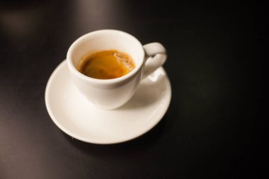 Koyu arka planda bir fincanda taze yapılmış kahve.