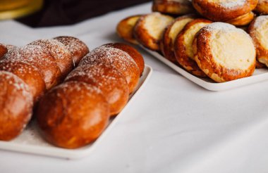 Beyaz masa arkaplanındaki bir tabakta süzme peynirli çörek.