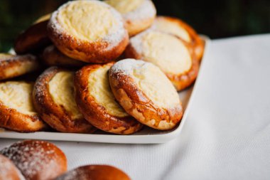 Beyaz masa arkaplanındaki bir tabakta süzme peynirli çörek.