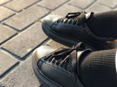 Unisex siyah ayakkabılar kaldırımlarda, yakın plan