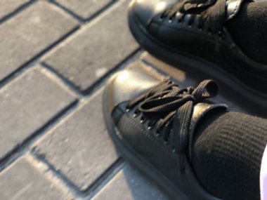 Unisex siyah ayakkabılar kaldırımlarda, yakın plan