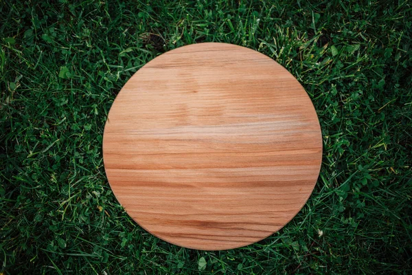 Yeşil çim arka planda yuvarlak ahşap tahta