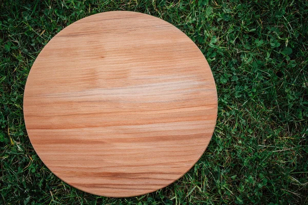 Yeşil çim arka planda yuvarlak ahşap tahta