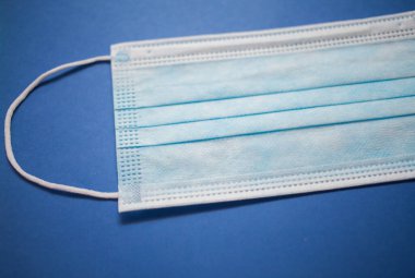 mavi arka plan üzerinde tek kullanımlık yüz maskesi