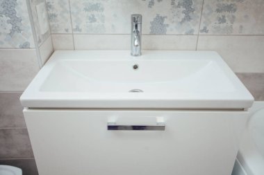 Modern bathroom wash basin with chrome faucet and gray tiling
