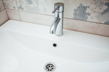 Modern banyo lavabosu krom musluk ve gri fayansla