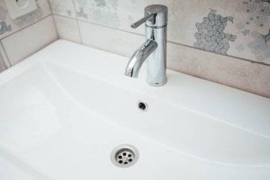 Modern banyo lavabosu krom musluk ve gri fayansla