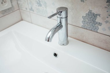 Modern banyo lavabosu krom musluk ve gri fayansla