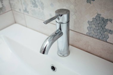 Modern banyo lavabosu krom musluk ve gri fayansla