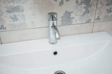 Modern banyo lavabosu krom musluk ve gri fayansla