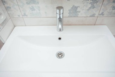 Modern banyo lavabosu krom musluk ve gri fayansla