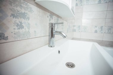 Modern banyo lavabosu krom musluk ve gri fayansla