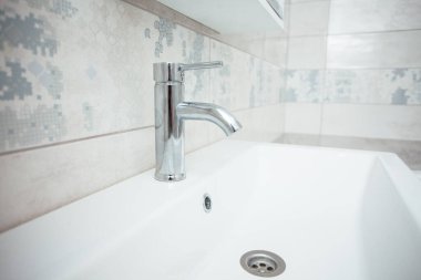 Modern bathroom wash basin with chrome faucet and gray tiling
