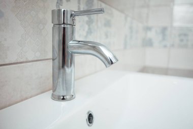 Modern banyo lavabosu krom musluk ve gri fayansla