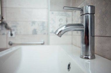 Modern banyo lavabosu krom musluk ve gri fayansla