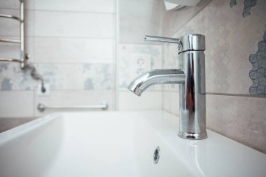 Modern banyo lavabosu krom musluk ve gri fayansla