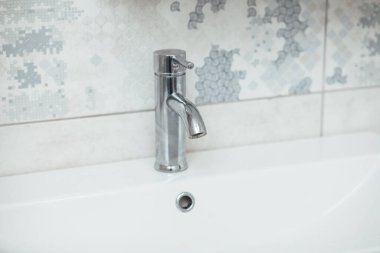 Modern banyo lavabosu krom musluk ve gri fayansla