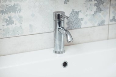 Modern banyo lavabosu krom musluk ve gri fayansla