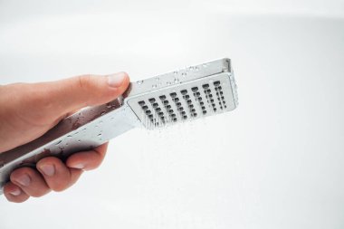 Erkek el banyoda beyaz duvara karşı duş alıyor, yakın çekim. 