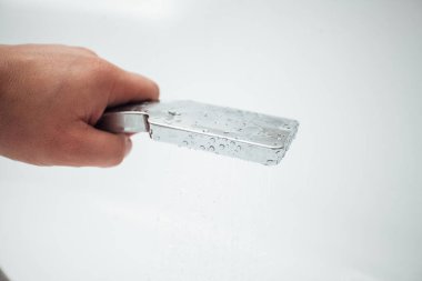 Erkek el banyoda beyaz duvara karşı duş alıyor, yakın çekim. 