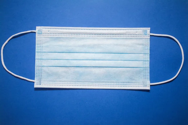 Disposable face mask on blue background
