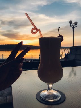 Bir bardak meyve suyu, gün batımı gökyüzü arka planı.