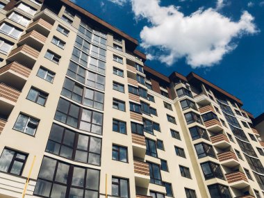 Güneşli bir günde mavi gökyüzü olan modern apartmanlar. Modern bir apartmanın cephesi