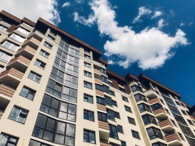 Güneşli bir günde mavi gökyüzü olan modern apartmanlar. Modern bir apartmanın cephesi