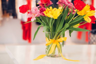 Vazoda düğümlenmiş fiyonk, suda çiçekler, farklı renklerde laleler, ev dekorasyonu.