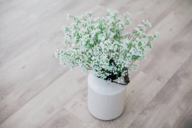 Metal bir vazoda beyaz çiçekler, saplı, antika, stüdyo dekorlu. 