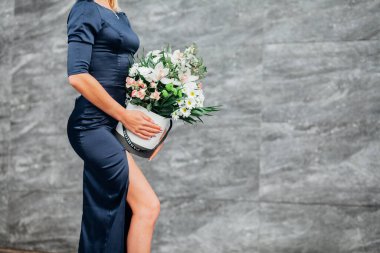 Kadın çiçekleri tutuyor, beyaz bir kutuda narin bir buket çiçek.