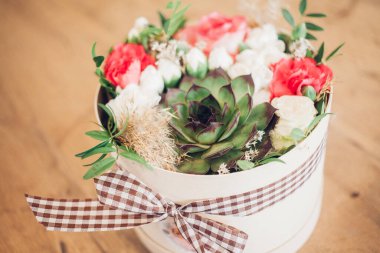 Şapka kutusunda güzel bir çiçek aranjmanı, ahşap arka plan. 