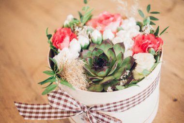 Şapka kutusunda güzel bir çiçek aranjmanı, ahşap arka plan. 