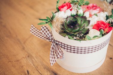 Şapka kutusunda güzel bir çiçek aranjmanı, ahşap arka plan. 