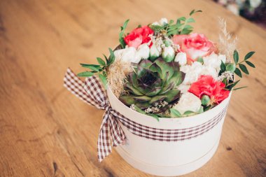 Şapka kutusunda güzel bir çiçek aranjmanı, ahşap arka plan. 