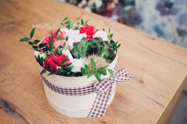 Şapka kutusunda güzel bir çiçek aranjmanı, ahşap arka plan. 