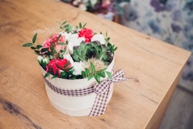 Şapka kutusunda güzel bir çiçek aranjmanı, ahşap arka plan. 