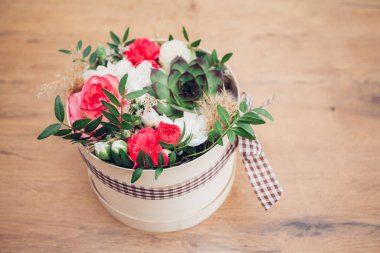 Şapka kutusunda güzel bir çiçek aranjmanı, ahşap arka plan. 