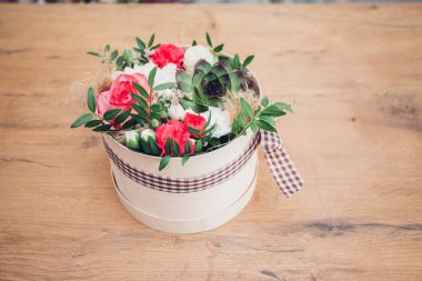 Şapka kutusunda güzel bir çiçek aranjmanı, ahşap arka plan. 