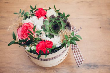 Şapka kutusunda güzel bir çiçek aranjmanı, ahşap arka plan. 