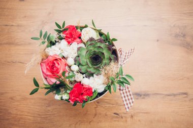 Şapka kutusunda güzel bir çiçek aranjmanı, ahşap arka plan. 