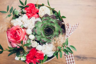 Şapka kutusunda güzel bir çiçek aranjmanı, ahşap arka plan. 