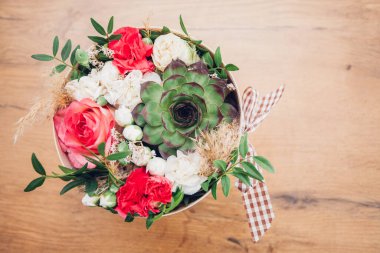 Şapka kutusunda güzel bir çiçek aranjmanı, ahşap arka plan. 